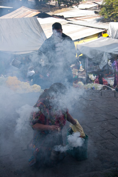 A female Mayan shaman burns incense before the door to the church.